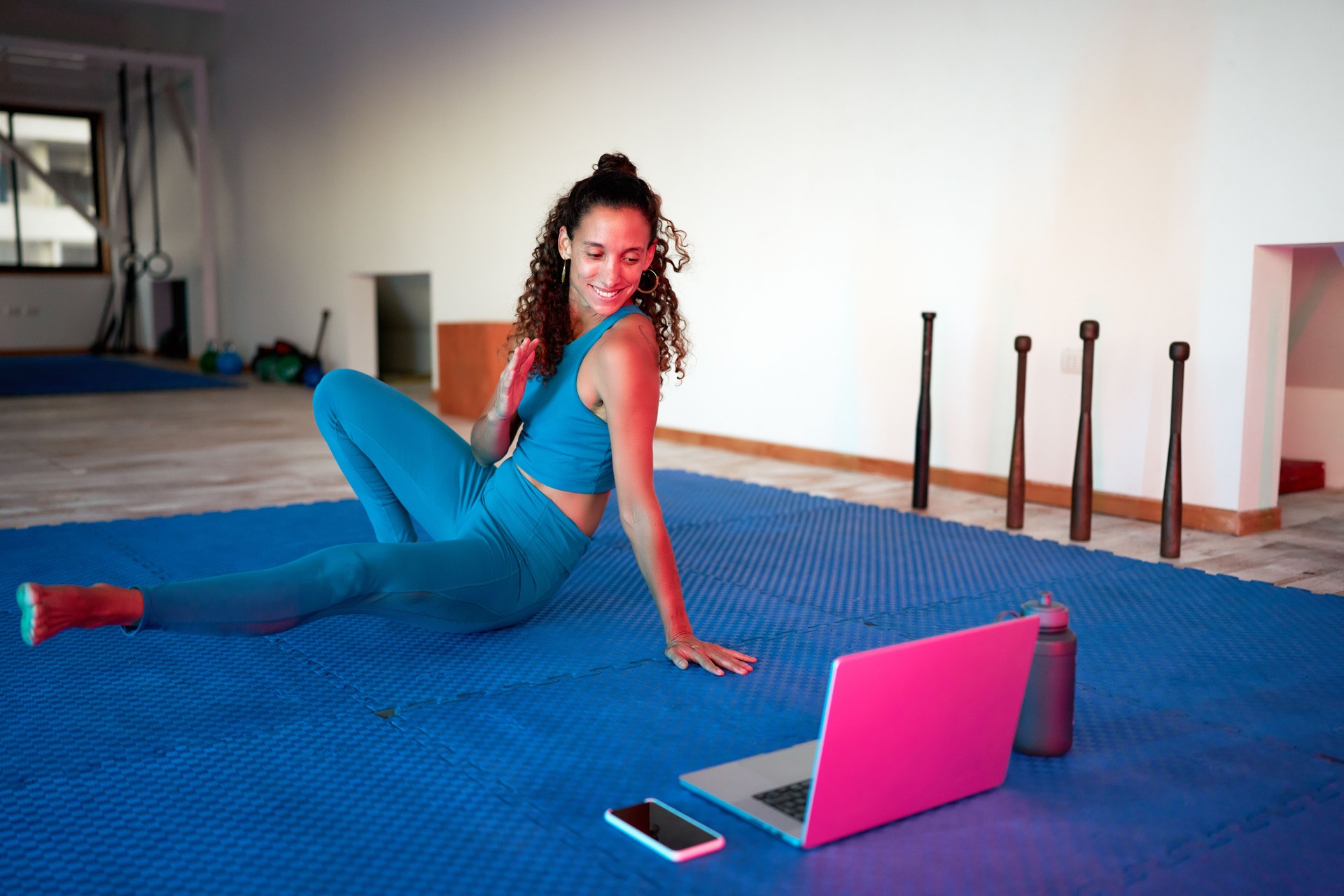 beautiful mid adult latina woman doing yoga fitness class online indoors on her notebook